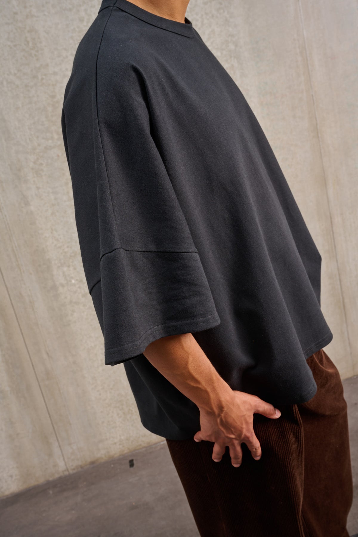 T-shirt oversize à col rond de la marque Aïdama, modèle Haku en jersey de coton noir. Porté par un mannequin homme et vu de profil.