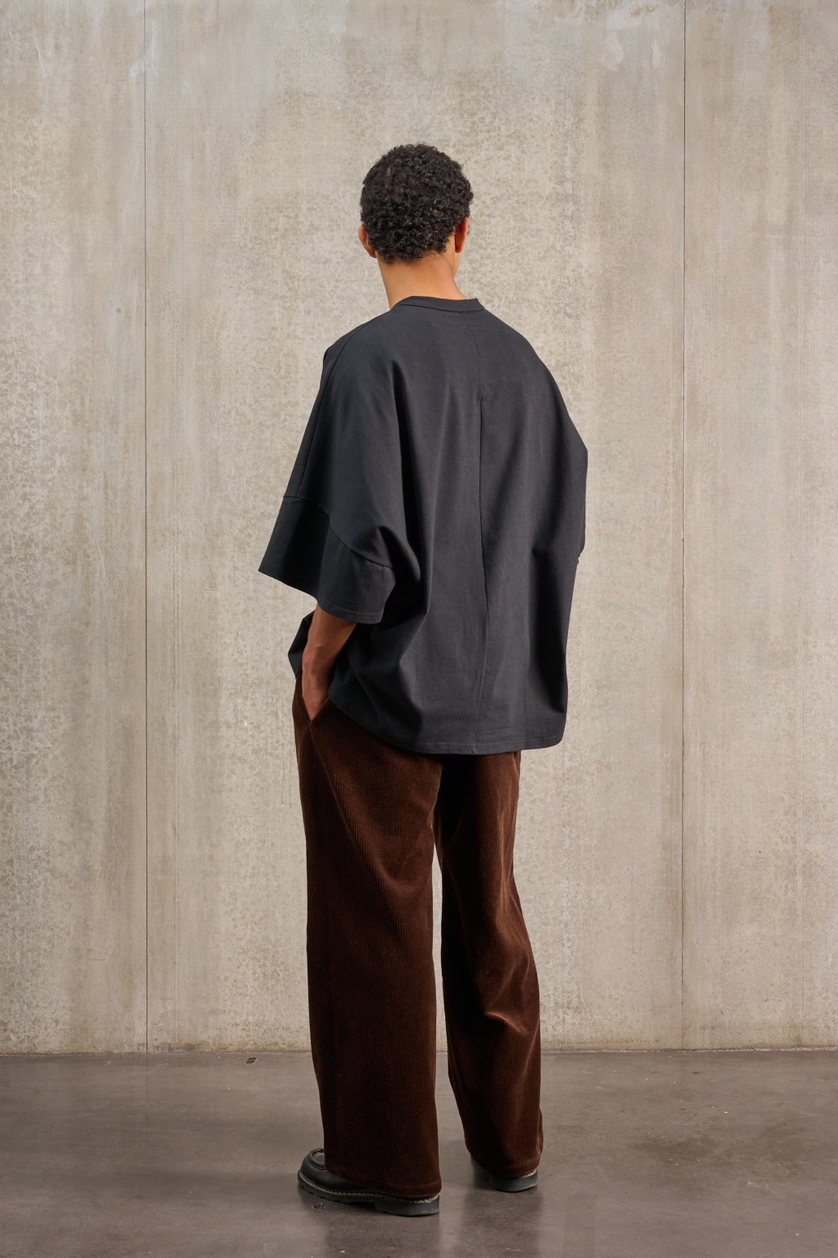T-shirt oversize à col rond de la marque Aïdama, modèle Haku en jersey de coton noir. Porté par un mannequin homme et vu de dos.