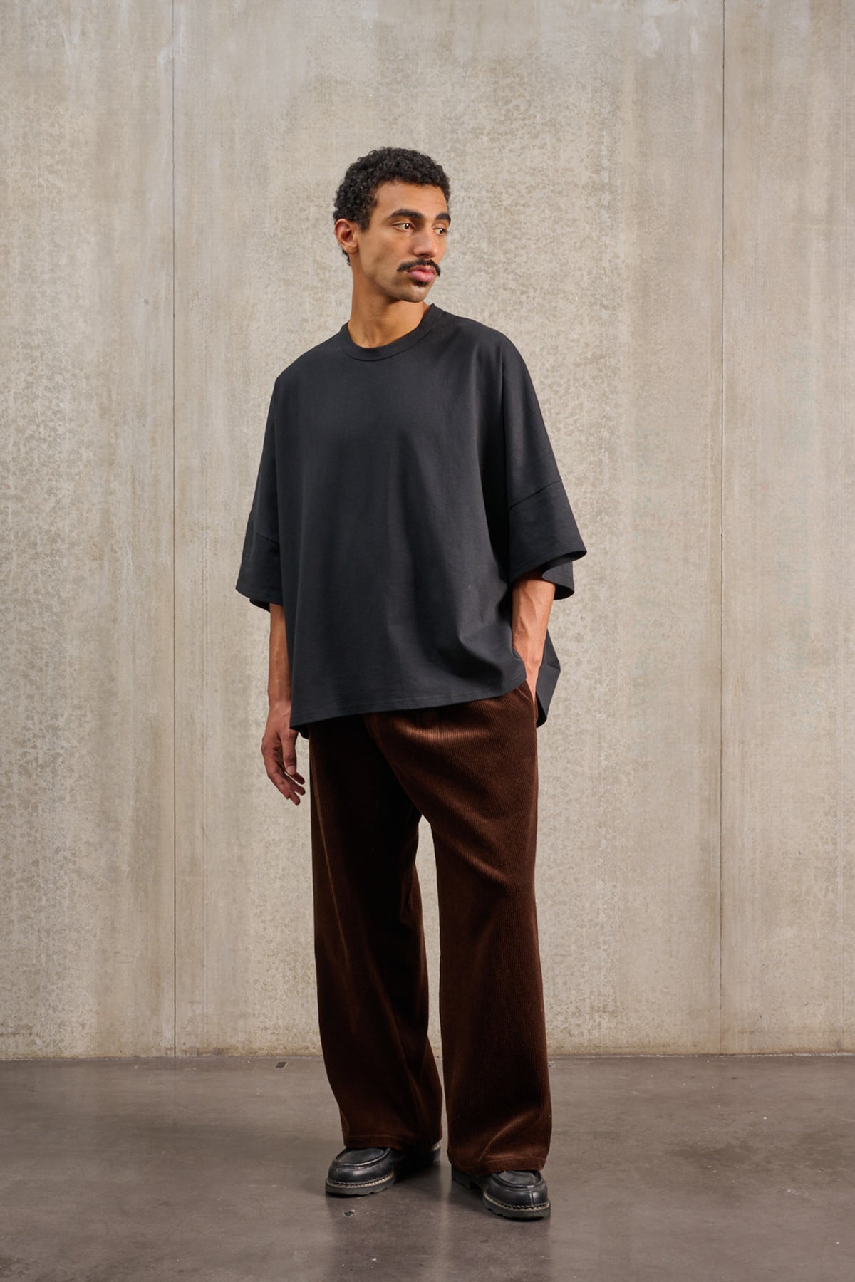 T-shirt oversize à col rond de la marque Aïdama, modèle Haku en jersey de coton noir. Porté par un mannequin homme et vu de face.