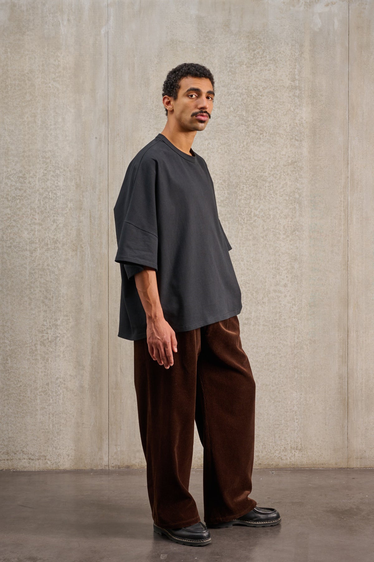 T-shirt oversize à col rond de la marque Aïdama, modèle Haku en jersey de coton noir. Porté par un mannequin homme et vu de trois quarts.