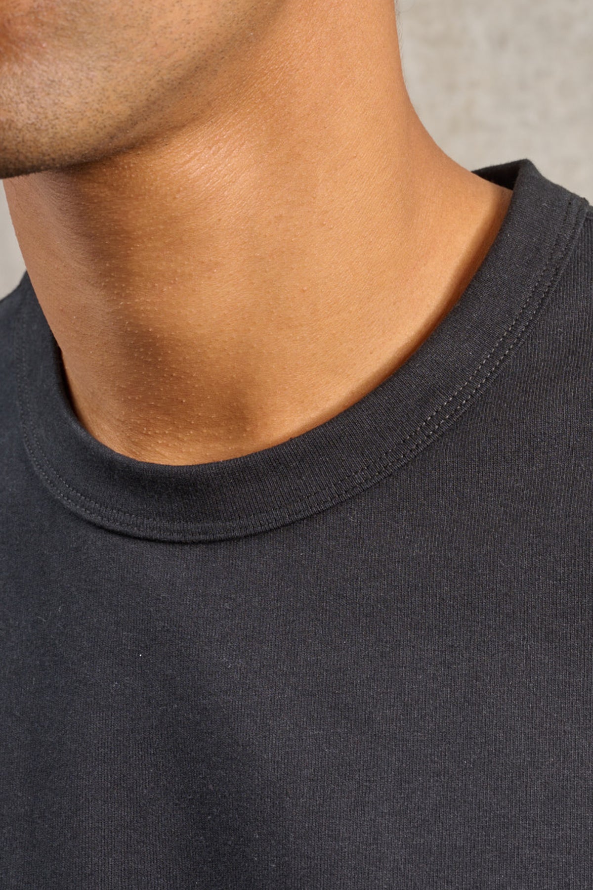 T-shirt oversize à col rond de la marque Aïdama, modèle Haku en jersey de coton noir. Porté par un mannequin homme et vu zoomé sur le col.