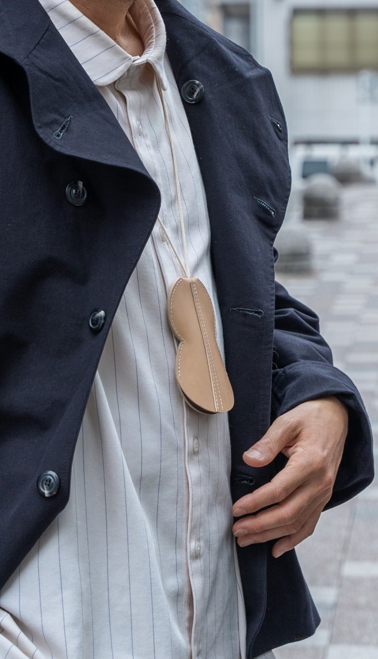 Tour de cou porte-cartes et porte-clés Hyotan de la marque Aïdama en cuir de vachette beige. Porté par un mannequin homme et vu de profil.