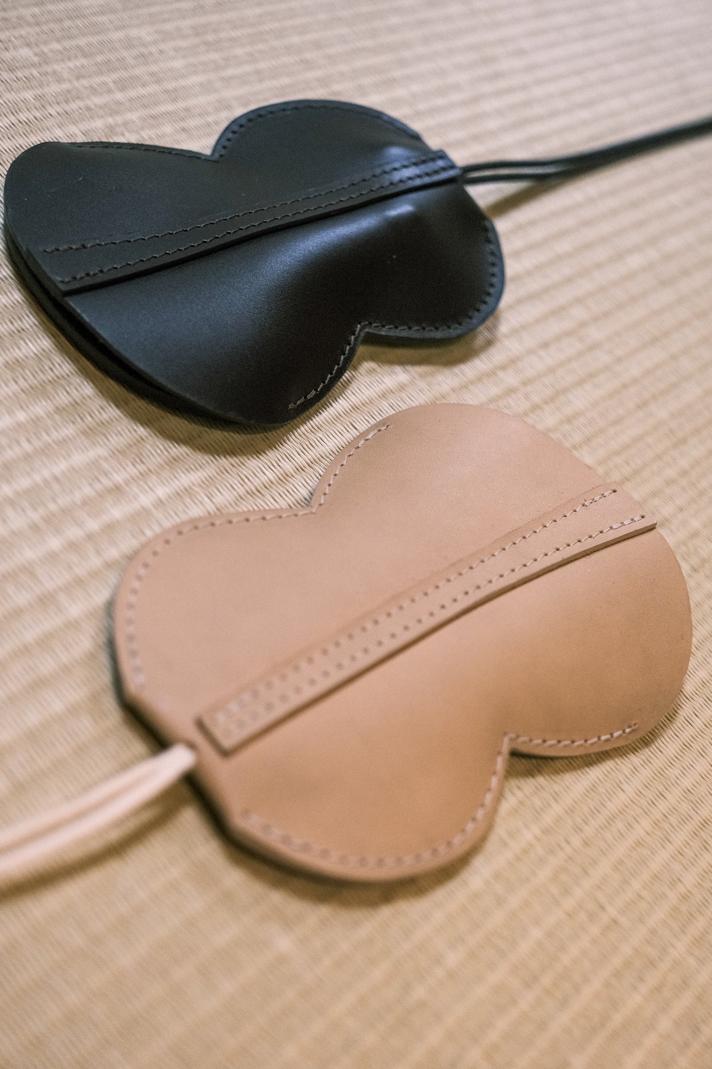 Tours de cou portes-cartes et portes-clés Hyotan de la marque Aïdama en cuir de vachette beige et acajou. Posés sur un tatami côte à côte.