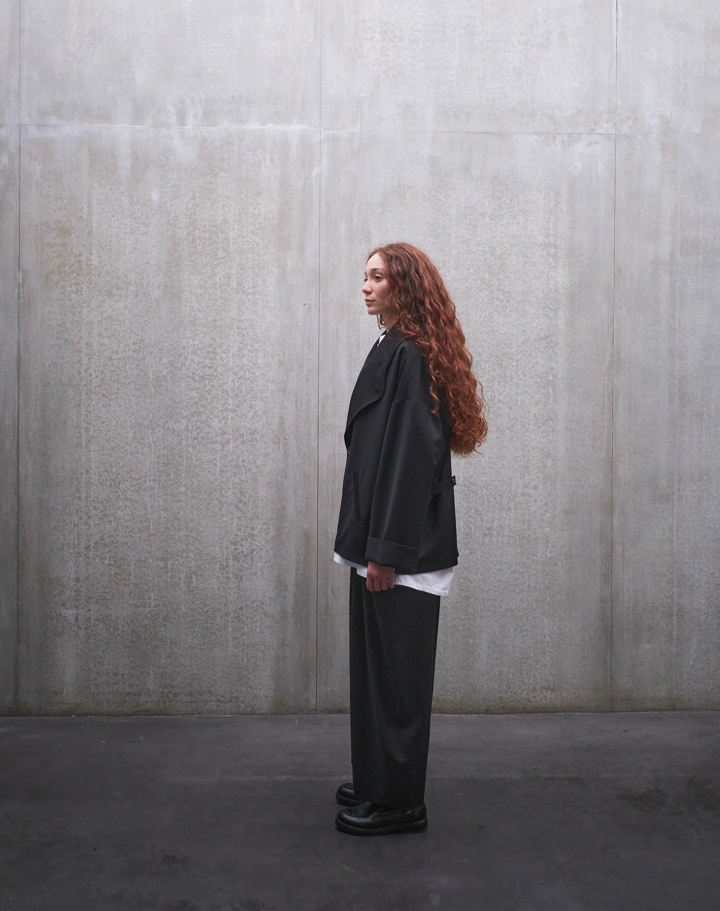 Veste oversize Aïdama, modèle Gunbai en laine froide noire. Portée fermée par une mannequin femme et vue de profil.