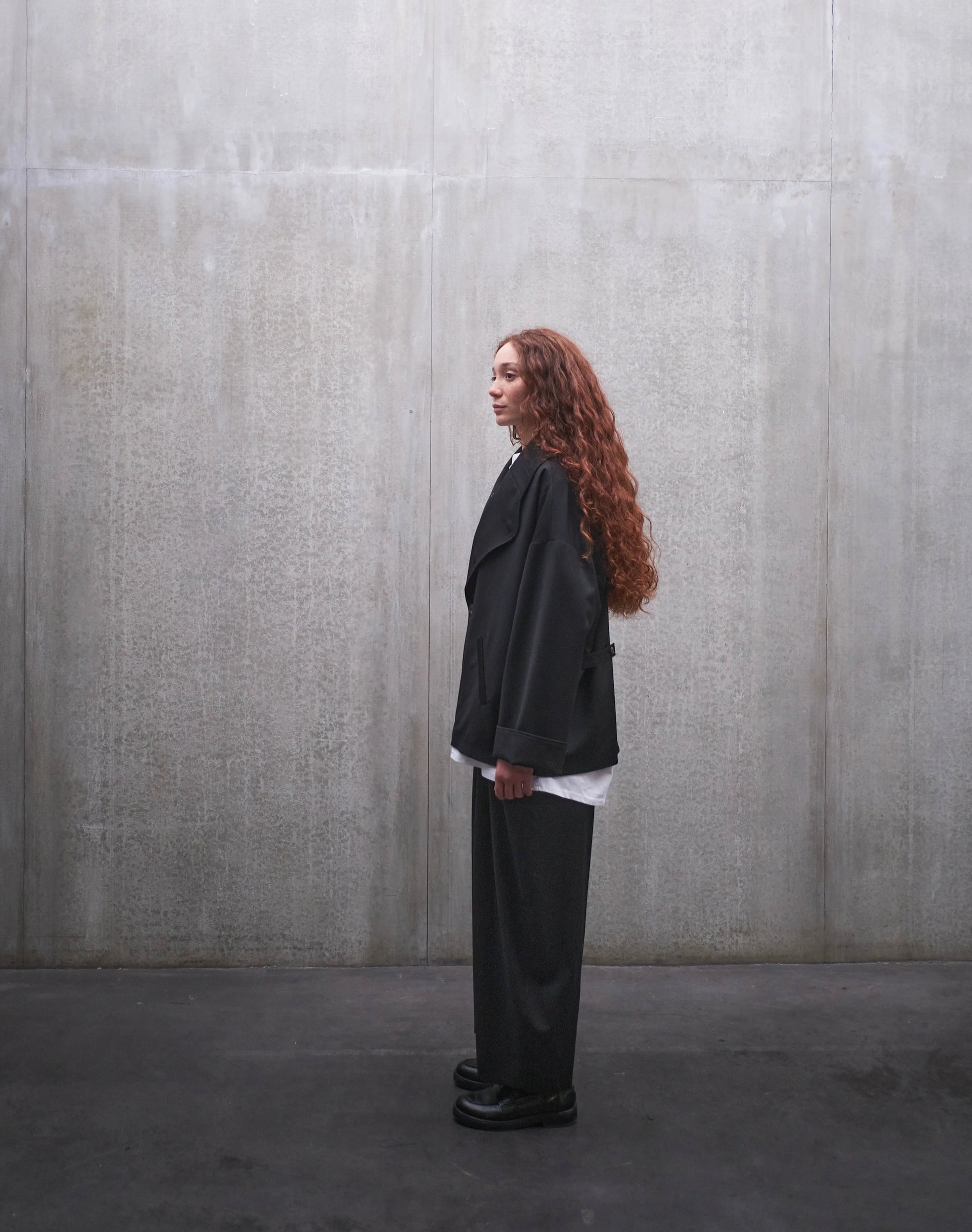 Veste oversize Aïdama, modèle Gunbai en laine froide noire. Portée fermée par une mannequin femme et vue de profil.
