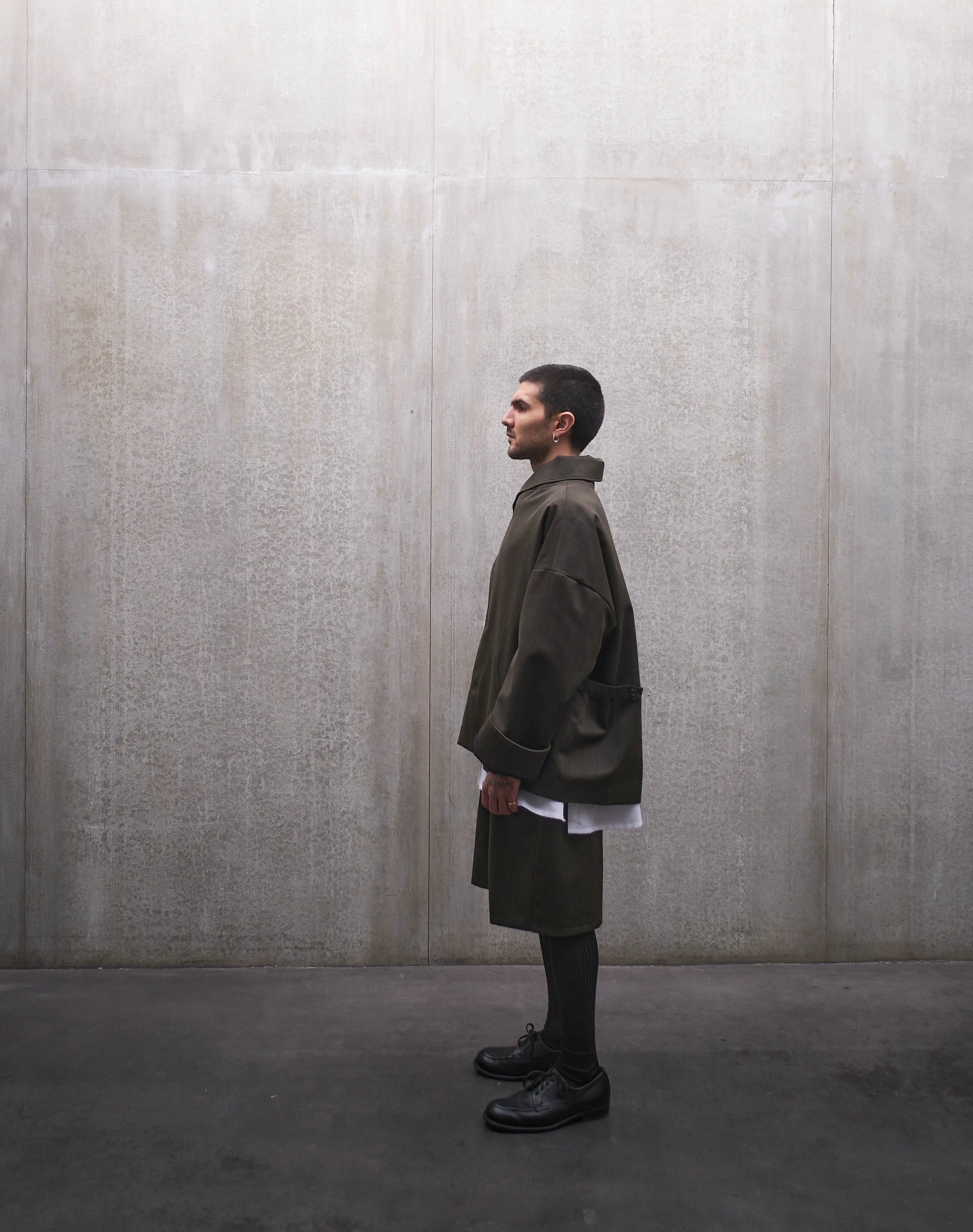 Veste oversize Aïdama, modèle Gunbai en laine froide vert chiné. Portée fermée par un mannequin homme et vue de profil.