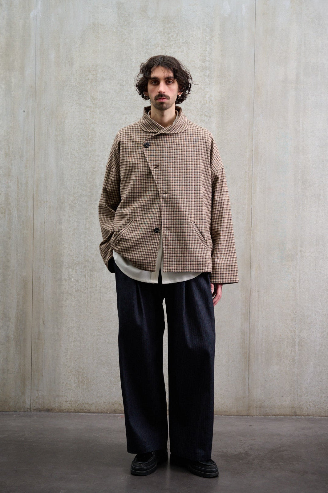 Veste oversize à col arrondi de la marque Aïdama, modèle Gunbai en laine marron à motif Vichy. Portée fermée par un mannequin homme et vue de face.