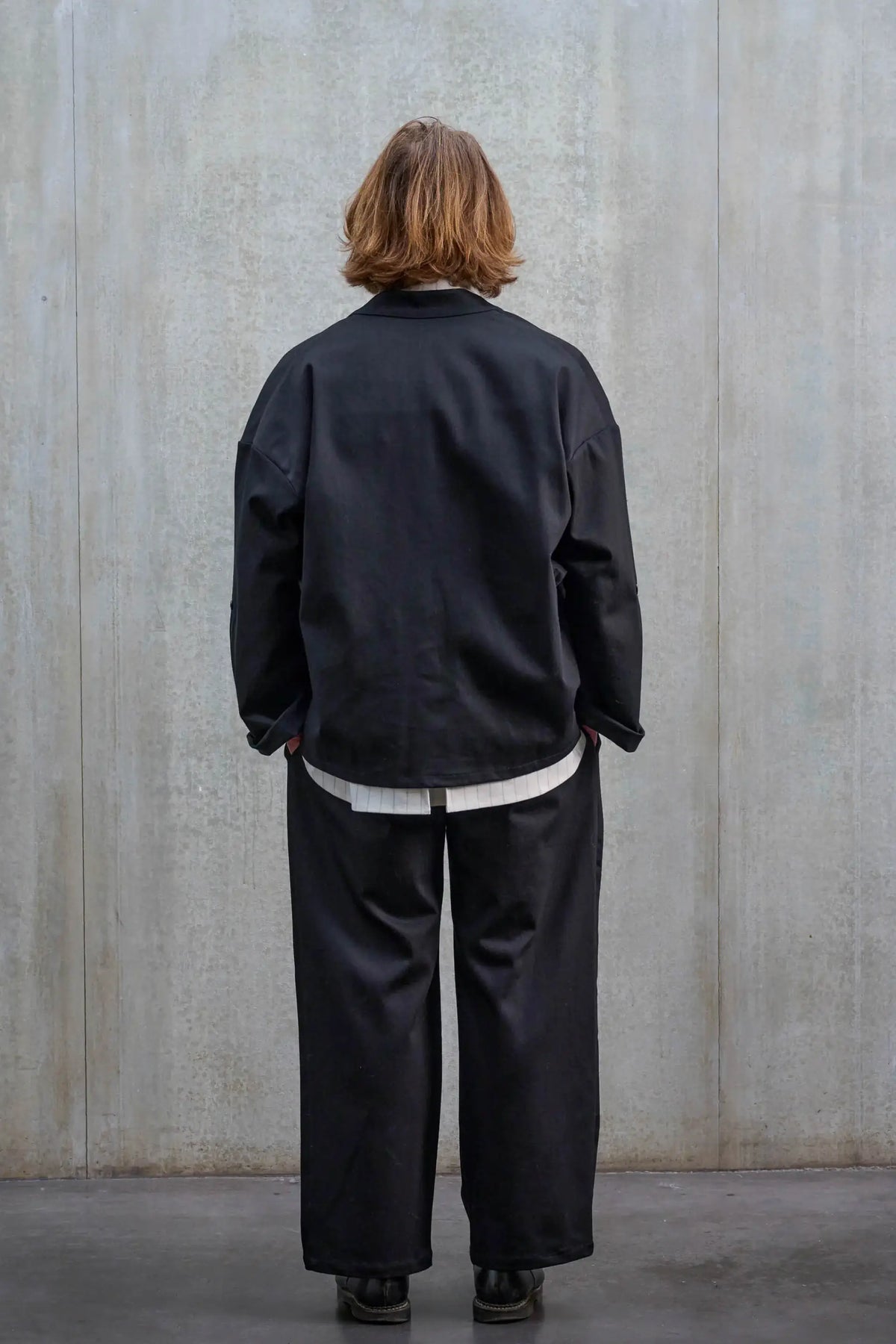 Veste oversize à col kimono de la marque Aïdama, modèle Samue en sergé de coton noir. Portée ouverte par un mannequin homme et vue de dos.