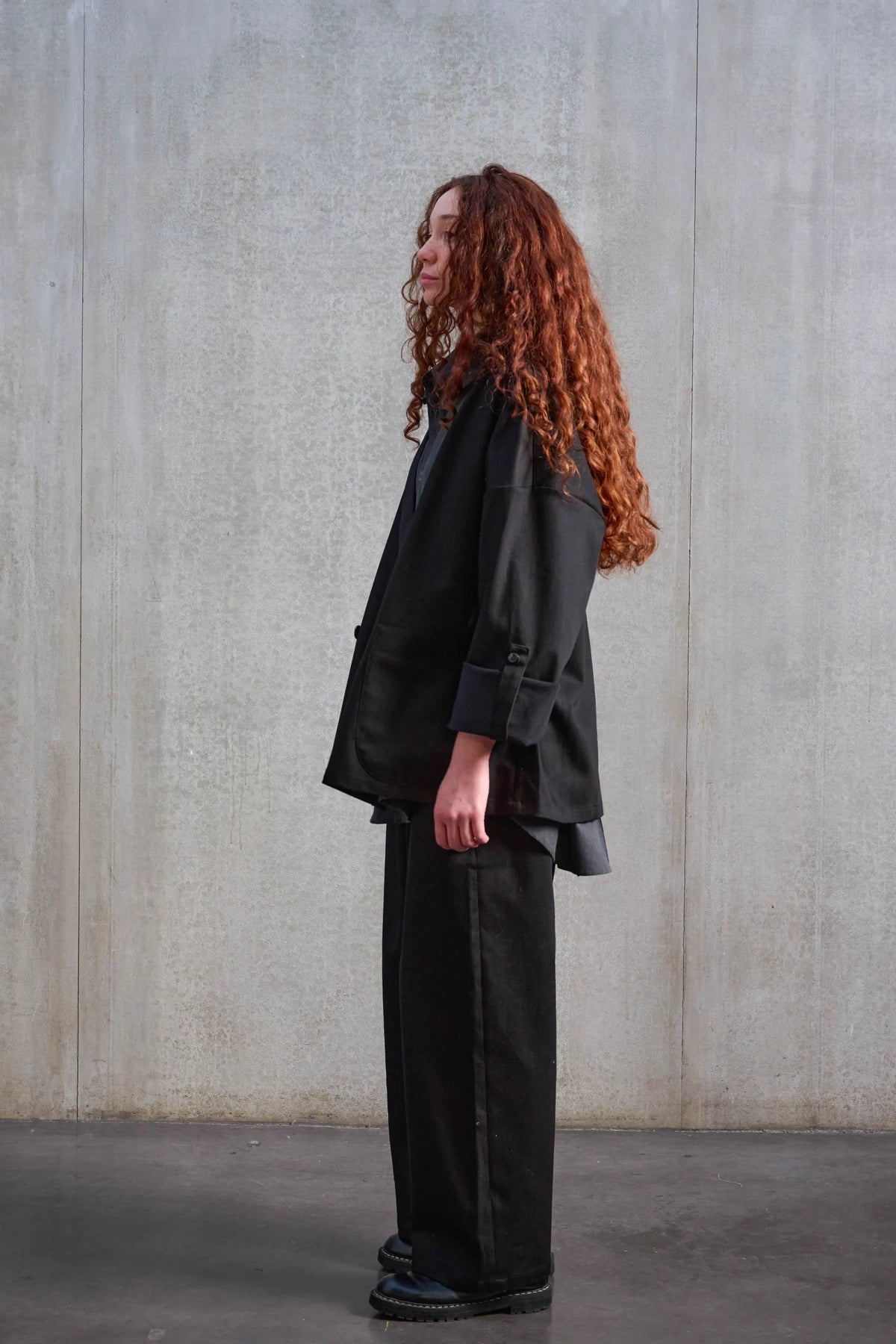 Veste oversize à col kimono de la marque Aïdama, modèle Samue en sergé de coton noir. Portée ouverte par une mannequin femme et vue de profil.