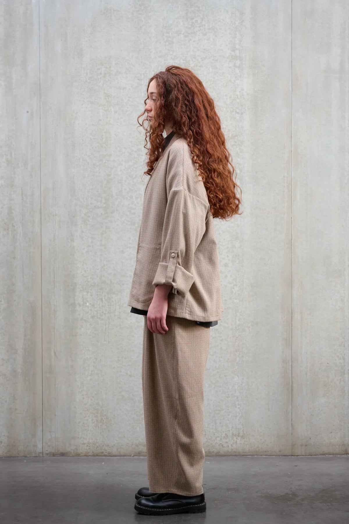 Veste oversize à col kimono de la marque Aïdama, modèle Samue en laine marron à motif pied de poule. Portée fermée par une mannequin femme et vue de profil.