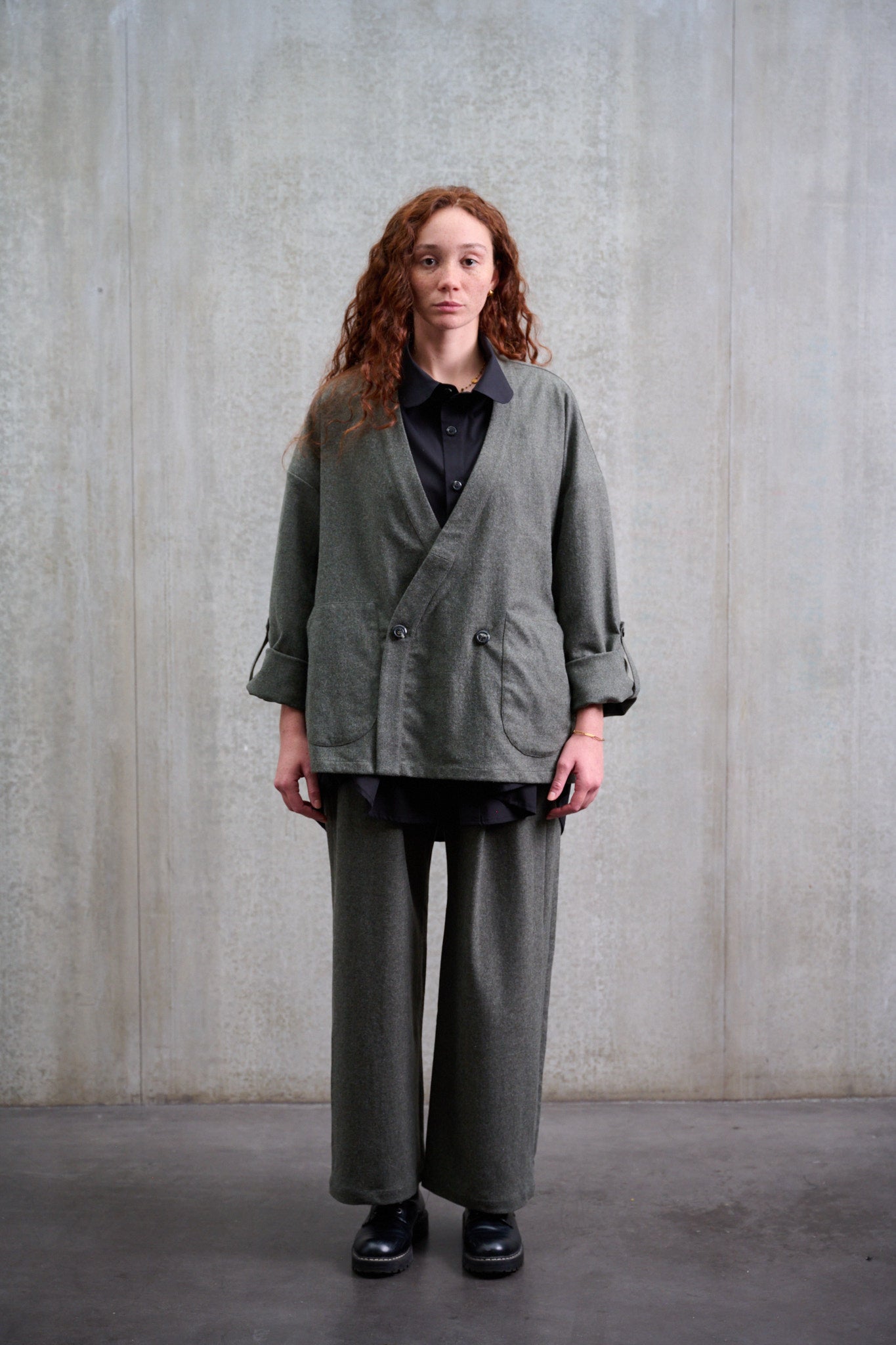 Veste croisée oversize à col kimono en flanelle de laine gris chiné portée fermée, de face et manches retroussées.