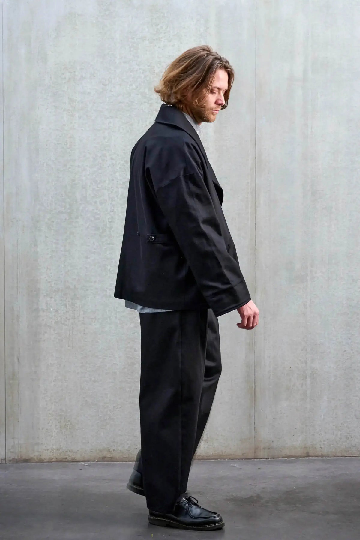 Veste oversize de la marque Aïdama, modèle Gunbai en sergé de coton noir. Portée ouverte par un mannequin homme et vue de profil.