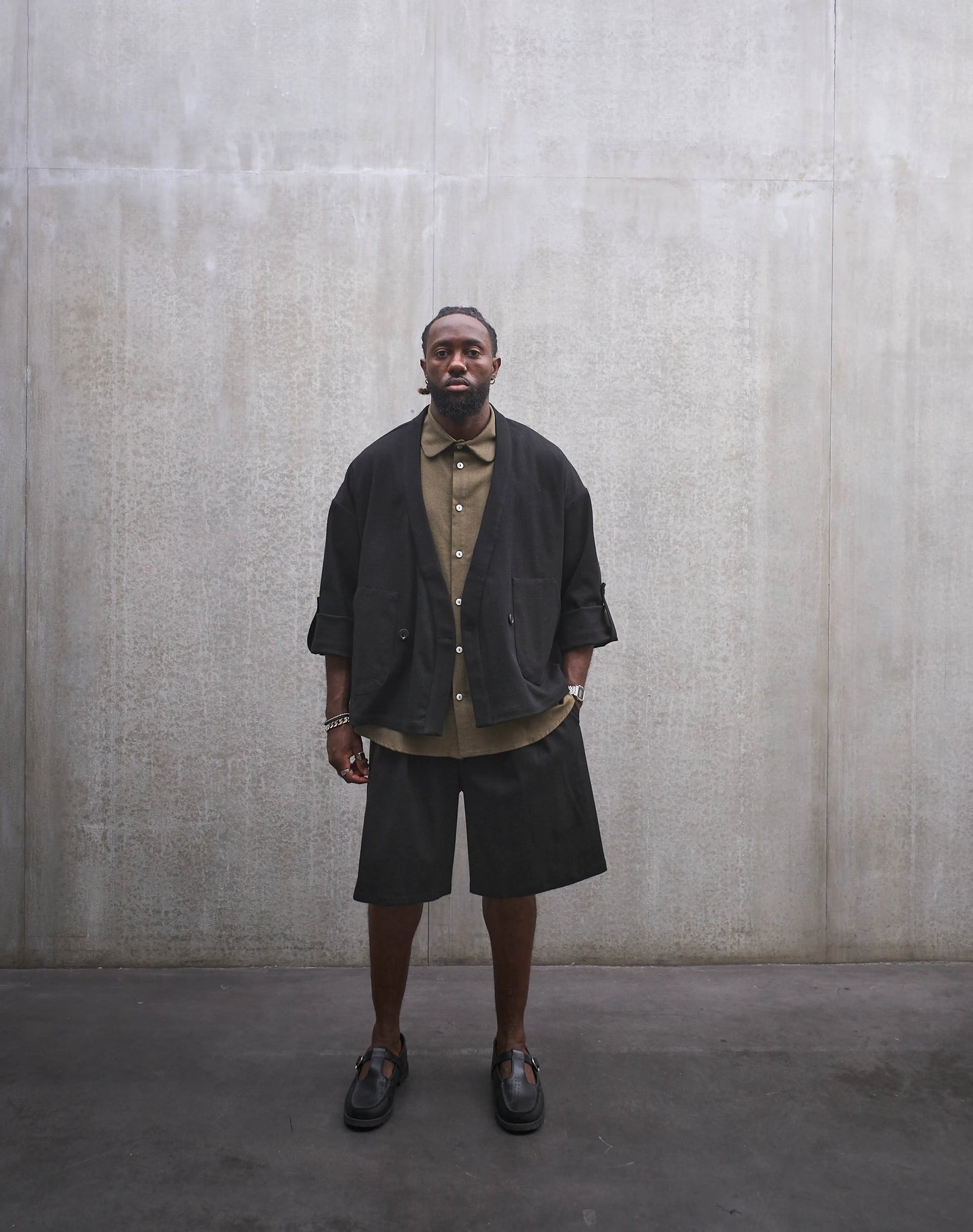 Veste croisée à col kimono Aïdama, modèle samue en coton noir à motif Prince de Galles ton sur ton. Portée ouverte par un mannequin homme et vue de face.