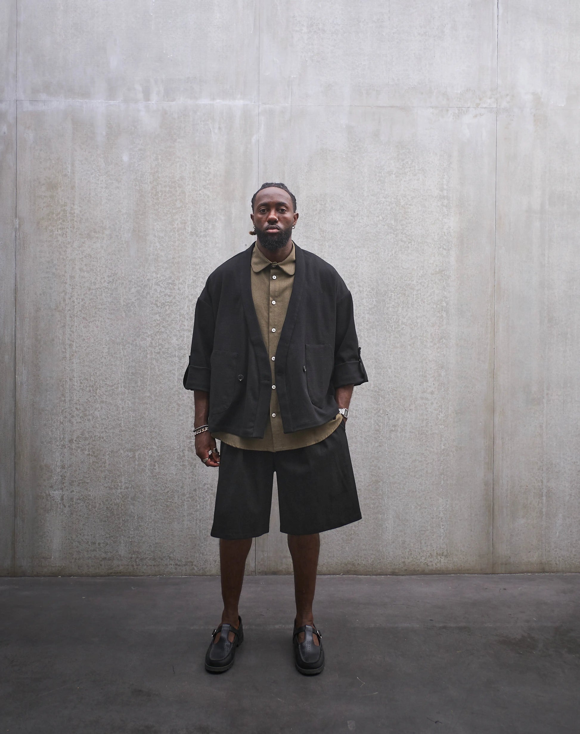 Veste croisée à col kimono Aïdama, modèle samue en coton noir à motif Prince de Galles ton sur ton. Portée ouverte par un mannequin homme et vue de face.